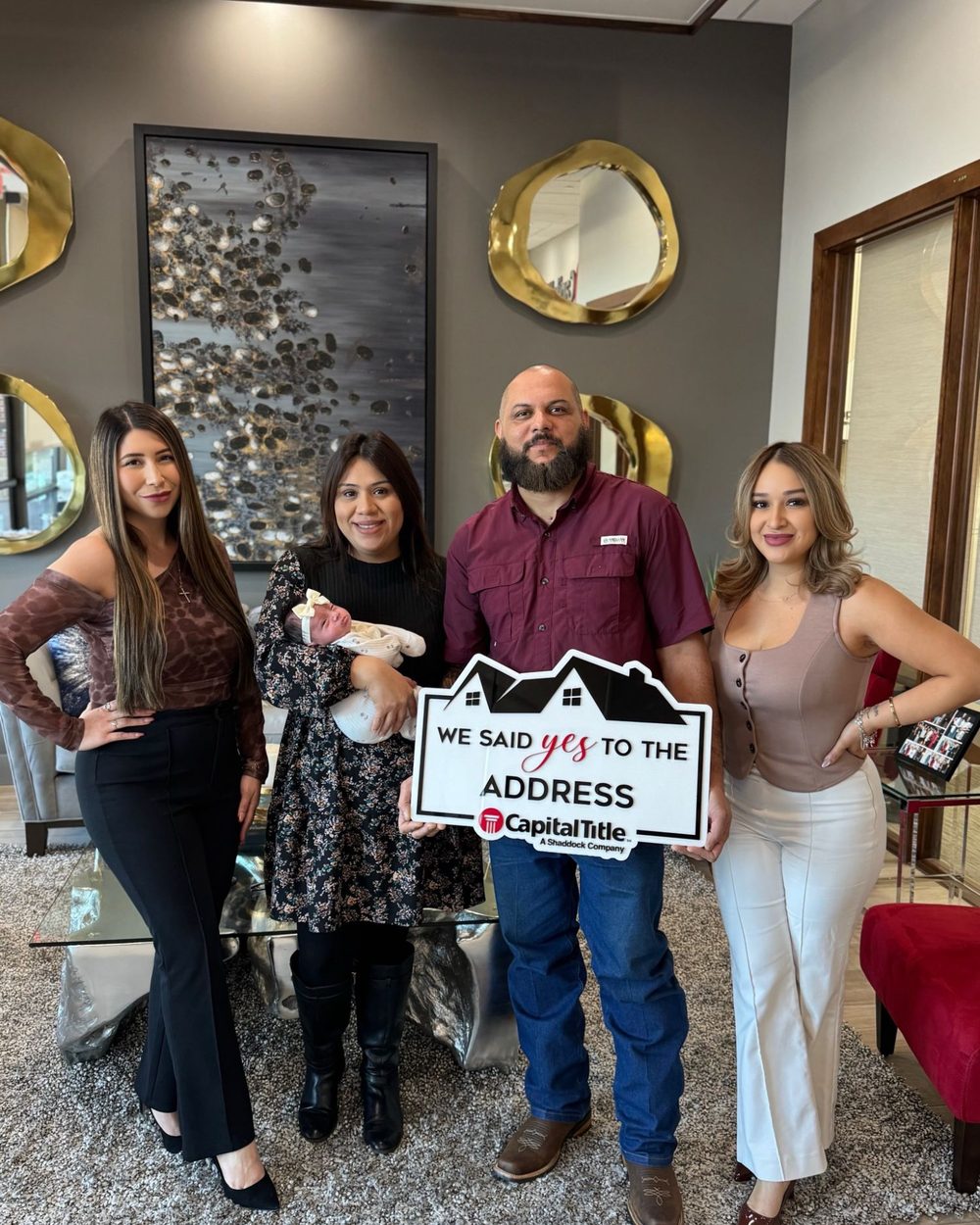 A family with their newborn holding a We Said Yes to the Address sign