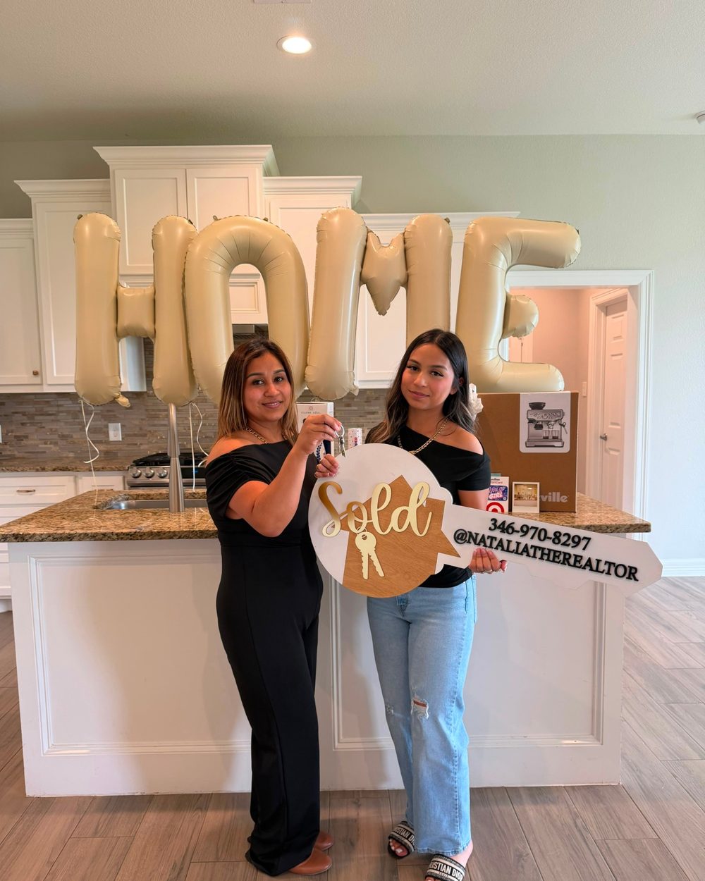 A buyer with a Sold key and HOME balloons in her new kitchen