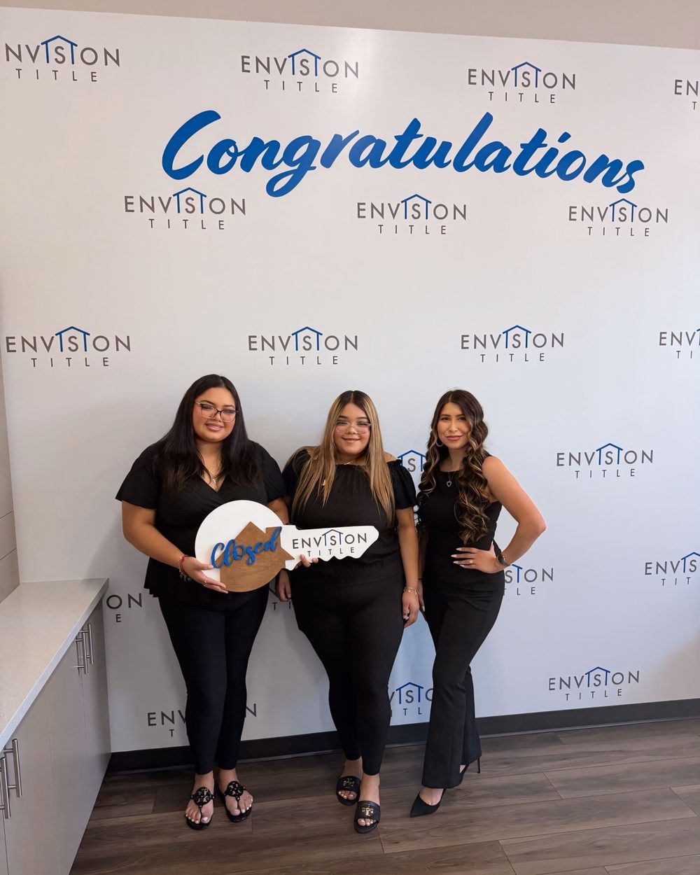 Buyers celebrating with a Closed key in front of a Congratulations wall