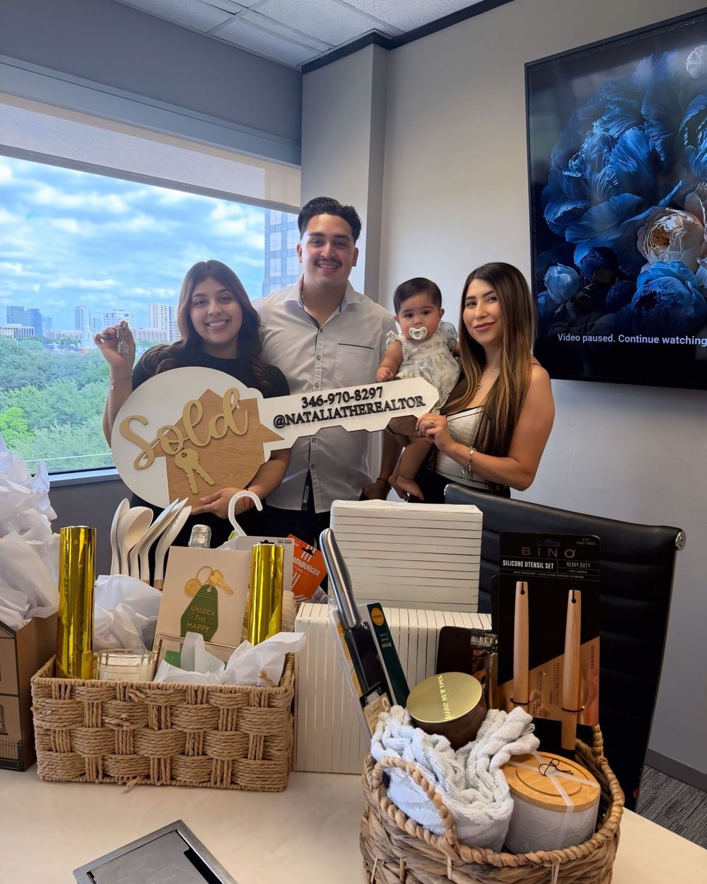 A family with their baby, a Sold key, and closing gift baskets