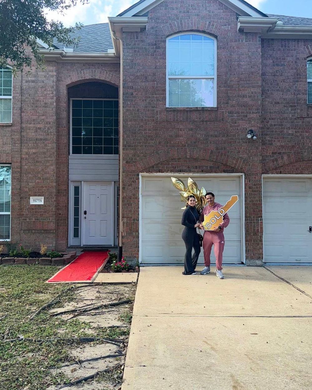 A couple with balloons and a Sold key in front of their new home