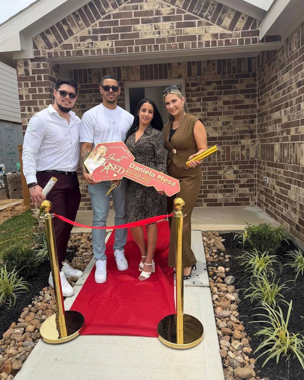 Buyers at a red carpet ribbon cutting outside their new home