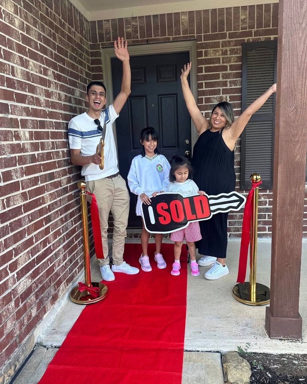 A family celebrating with a Sold key on their front porch