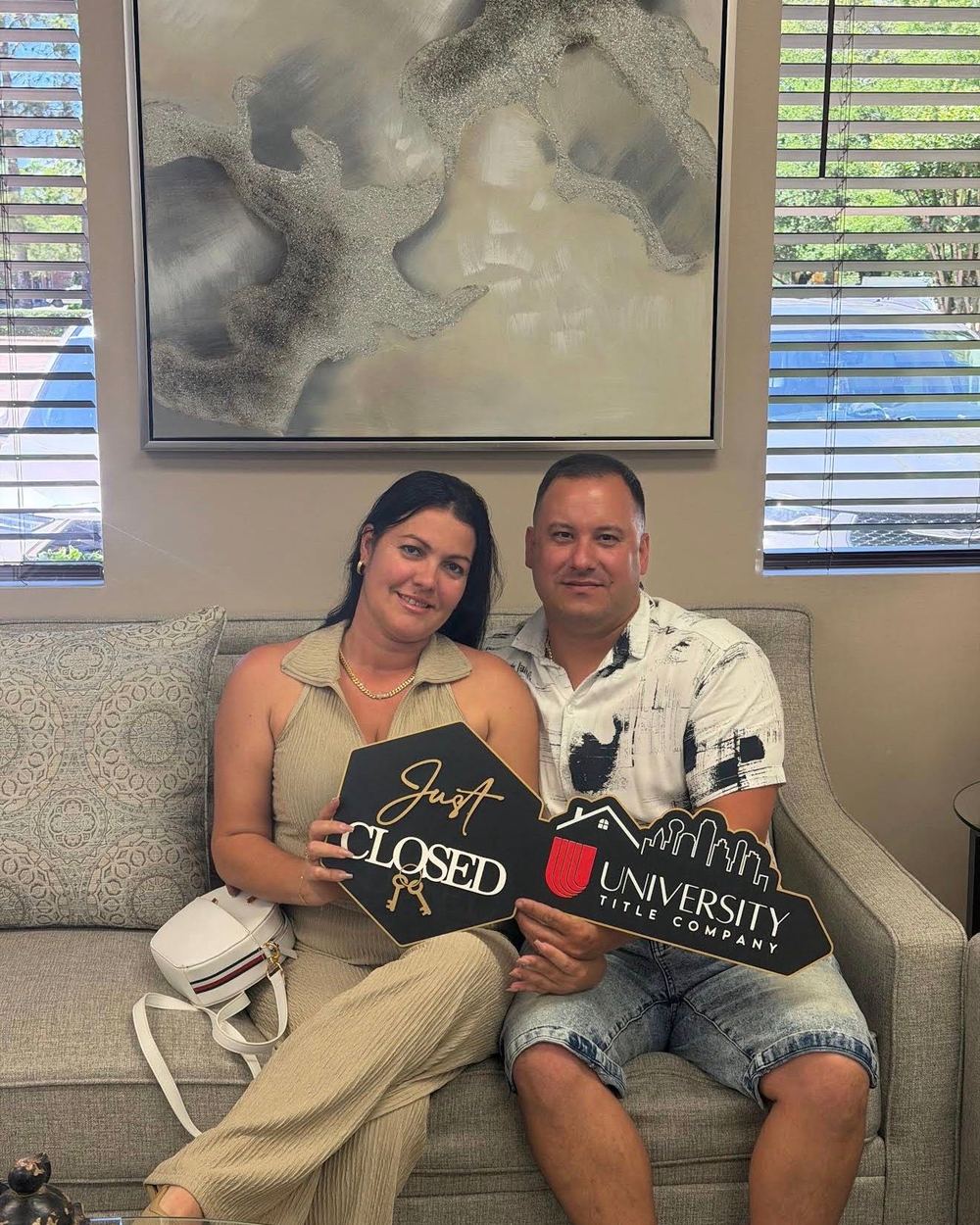A couple on a sofa holding a University Title Just Closed key