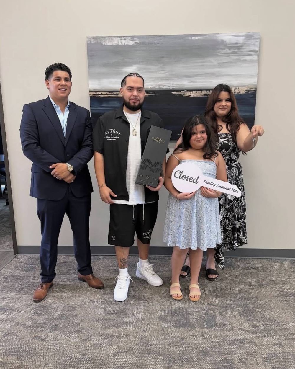 A family holding a Fidelity National Title Closed sign with their loan officer