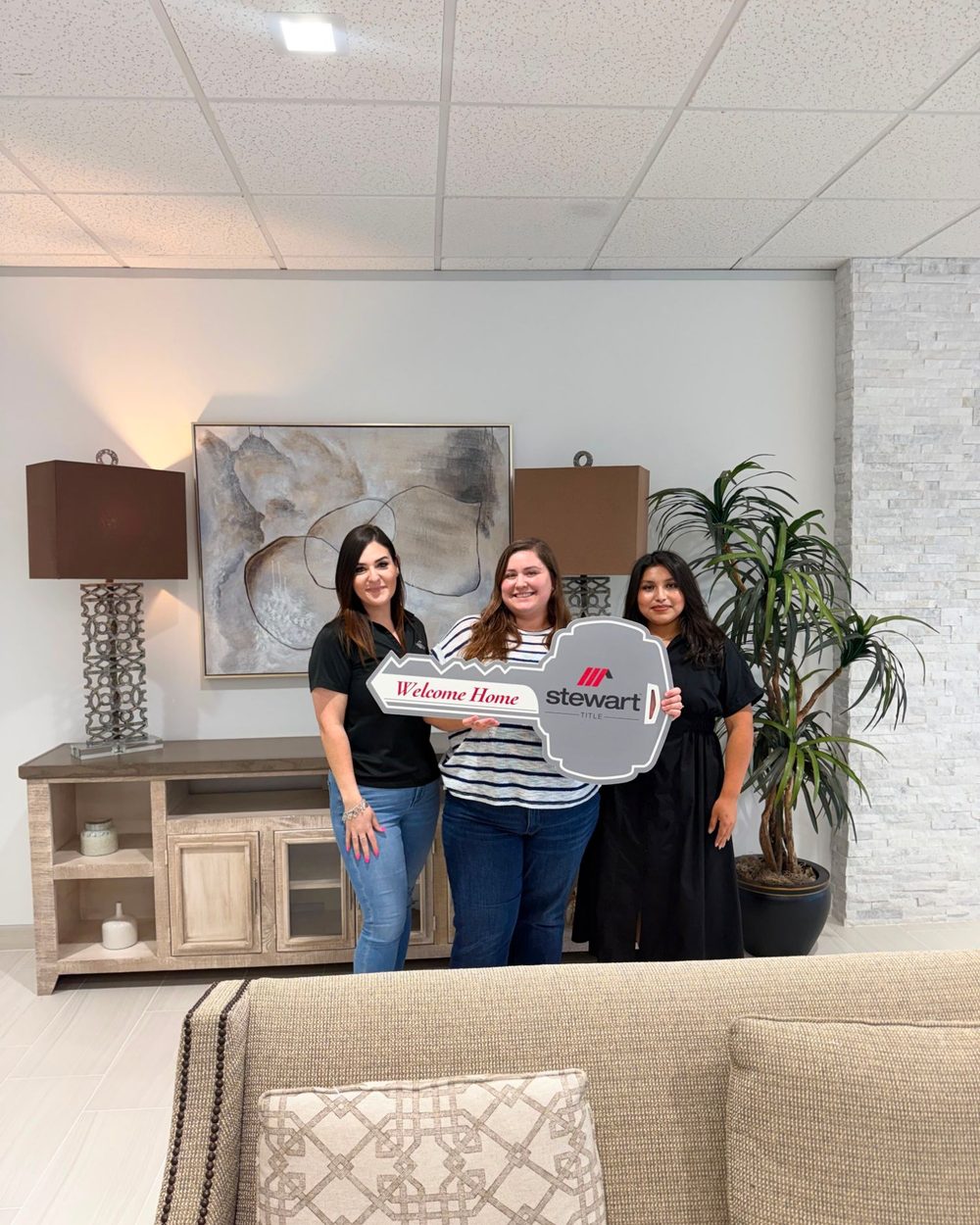 A buyer holding a Welcome Home key with Yesenia and her partner at the title company
