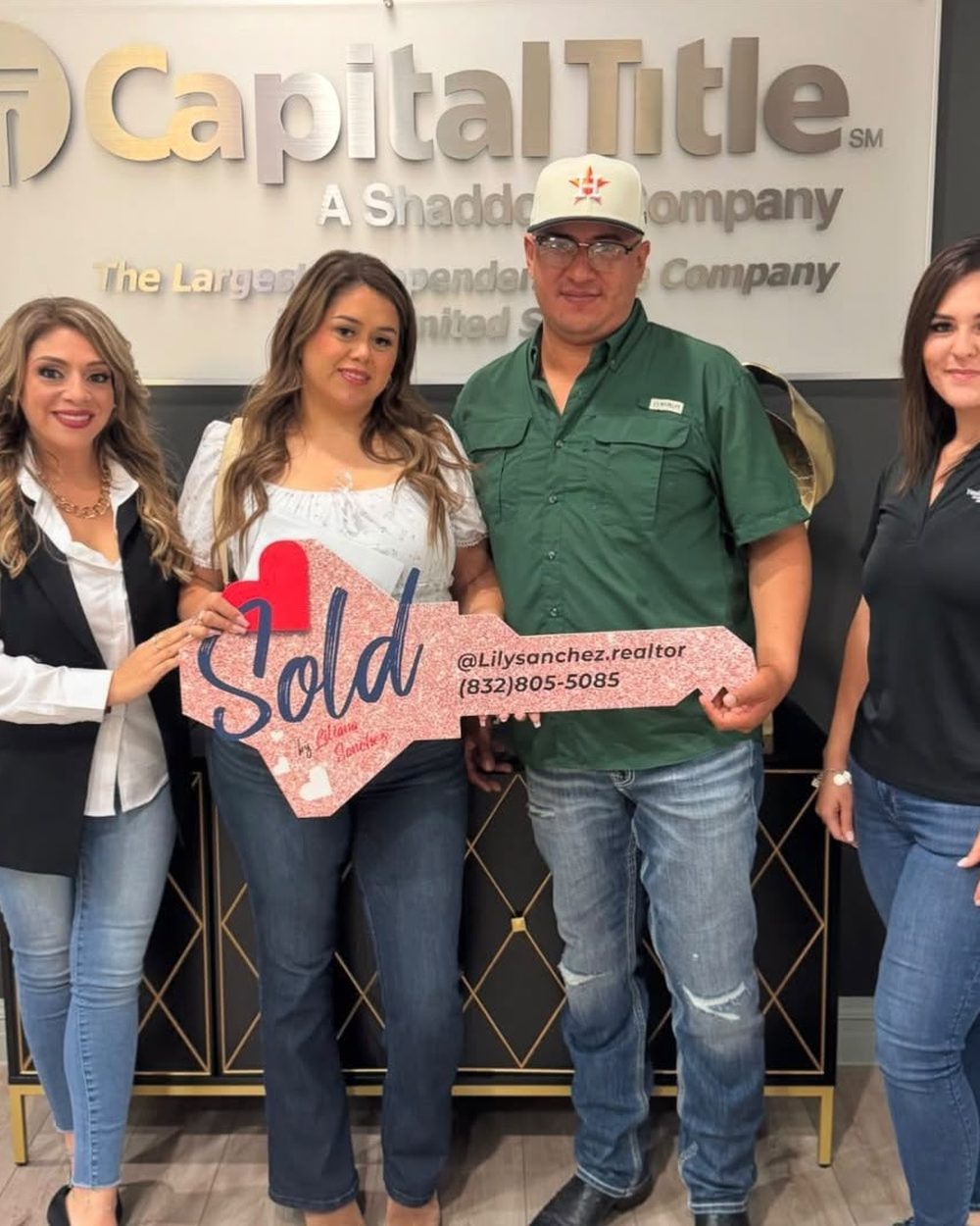 A couple celebrating with a Sold key beside Yesenia and their agent