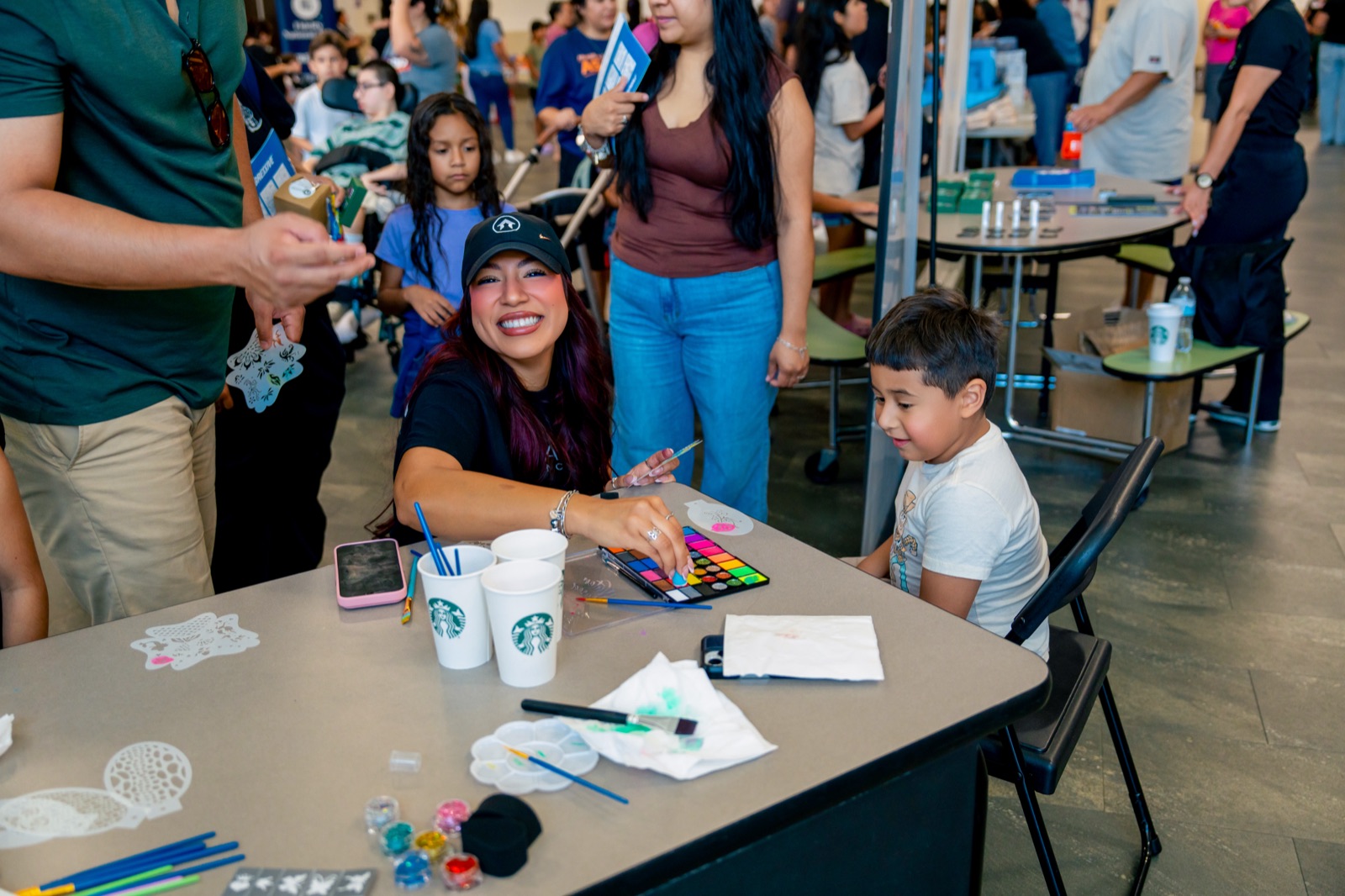 A volunteer painting a student's face at the craft table