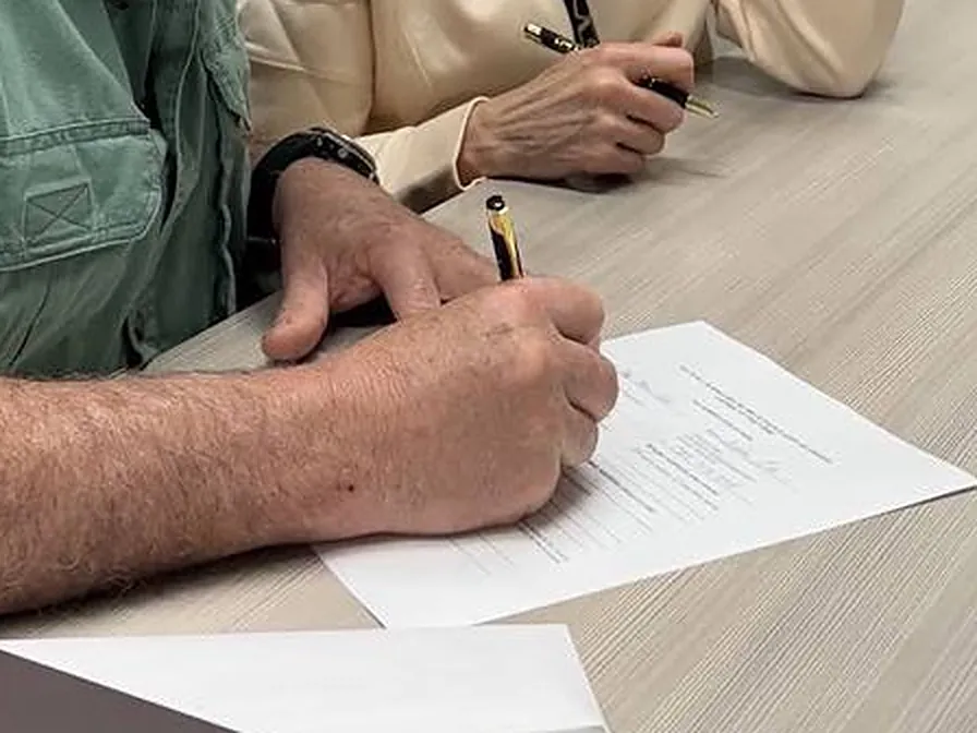 Hands signing a document at a table