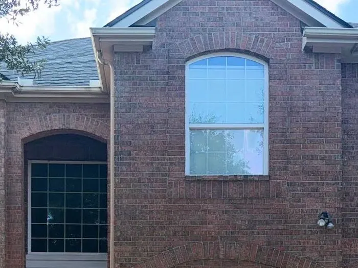 The brick front of a two-story home with an arched window