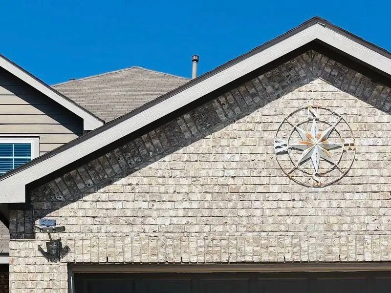 The brick front of a home with a peaked roof under a clear blue sky